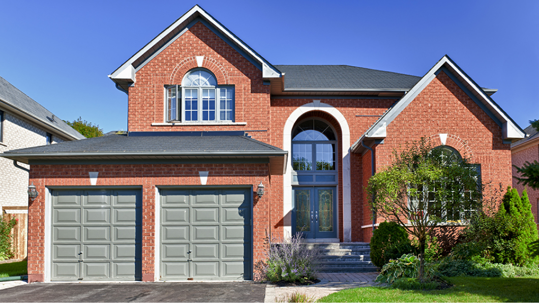 brick home with rounded entrance and gray garage door