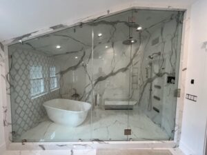 A large tiled shower with a glass door, and a tub on the inside