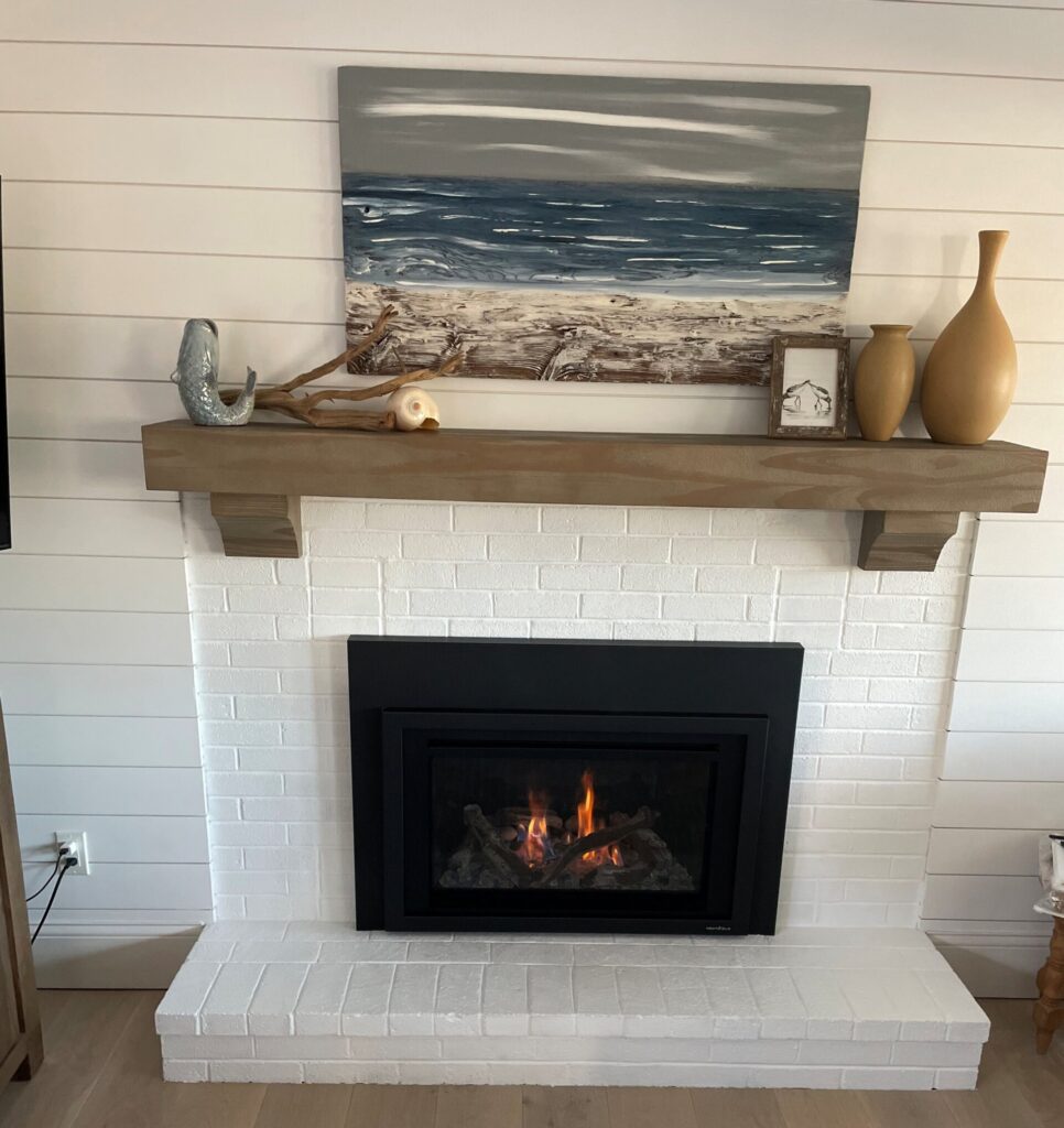 A fireplace with white brick and a wood mantle