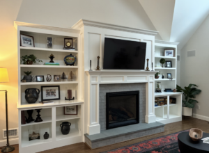 A new fireplace installed in a wall with built-in shelves and a tv above.