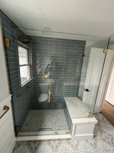 A recently renovated bathroom with a new tile shower with bench